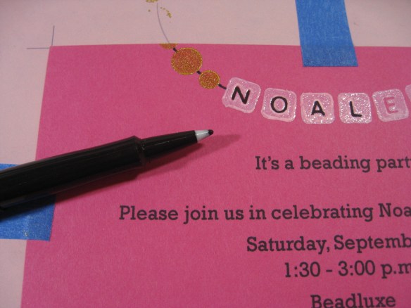photo of invitation and marker with bead strings and letters filled in black