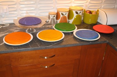 6 flat cakes, one each of orange, purple, yellow, red, blue, and green.