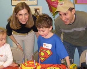 photo of birthday boy with superman 5 on tee shirt, name tag, and cake